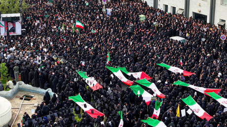 Mourners carrying Iranian flags and portraits as they gather during a funeral ceremony for children killed after a primary school was targeted in US and Israeli attacks, March 3, 2026, Minab, Iran.