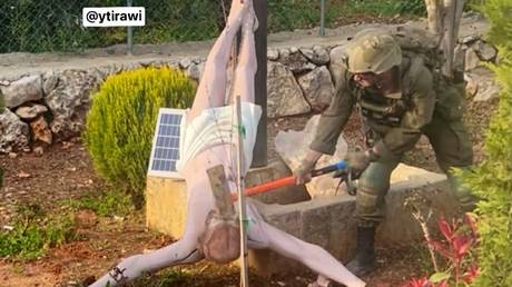 An Israeli soldier smashes a statue of Jesus Christ with a hammer in Dibil, southern Lebanon.