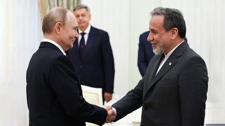 Russian President Vladimir Putin and Iranian Foreign Minister Abbas Araghchi shake hands before a meeting at the Kremlin in Moscow, Russia.