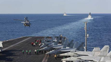 The aircraft carrier USS Abraham Lincoln (CVN 72) transits the Strait of Hormuz as an MH-60S Sea Hawk helicopter from the Nightdippers of Helicopter Sea Combat Squadron (HSC) 5 lifts off from the flight deck November 19, 2019