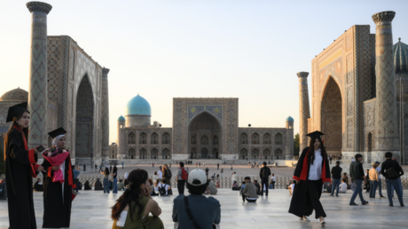 Young people gather in Registan Square, with the Tilya Kori Madrasa seen in the background, in Samarkand, Uzbekistan.