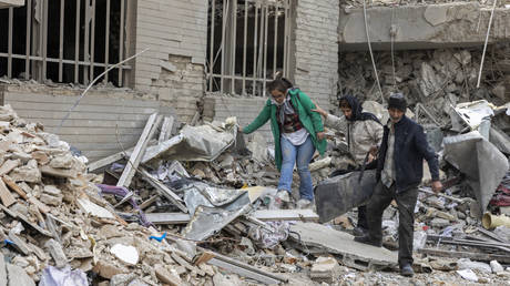 Civilians stand amid the rubble of residential buildings destroyed by US and Israeli strikes in Tehran, Iran, March 12, 2026.