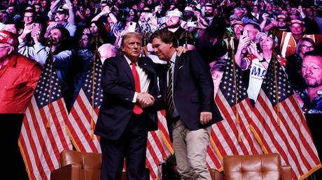 Donald Trump shakes hands with Tucker Carlson on October 31, 2024 in Phoenix, Arizona.
