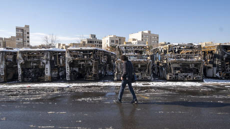 A man walks past burnt-out buses at a bus terminal in Tehran, Iran, on January 21, 2026.