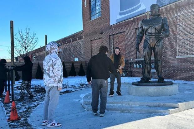 People pose for photos with a RoboCop statue