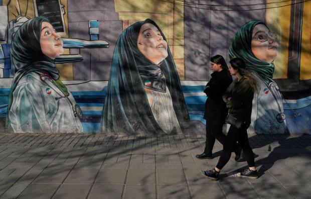 Women walk past a mural at a girls school 
