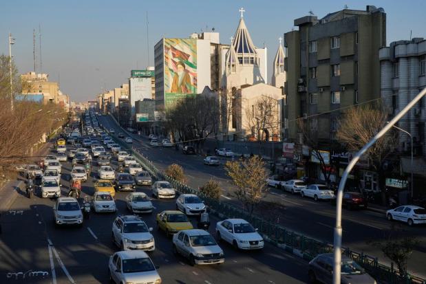Vehicles drive past the Saint Sarkis church and a painting of the late Iranian revolutionary founder Ayatollah Khomeini in downtown Tehran