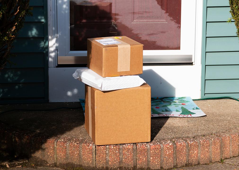 Three box packages delivered to the front door of a residential house.