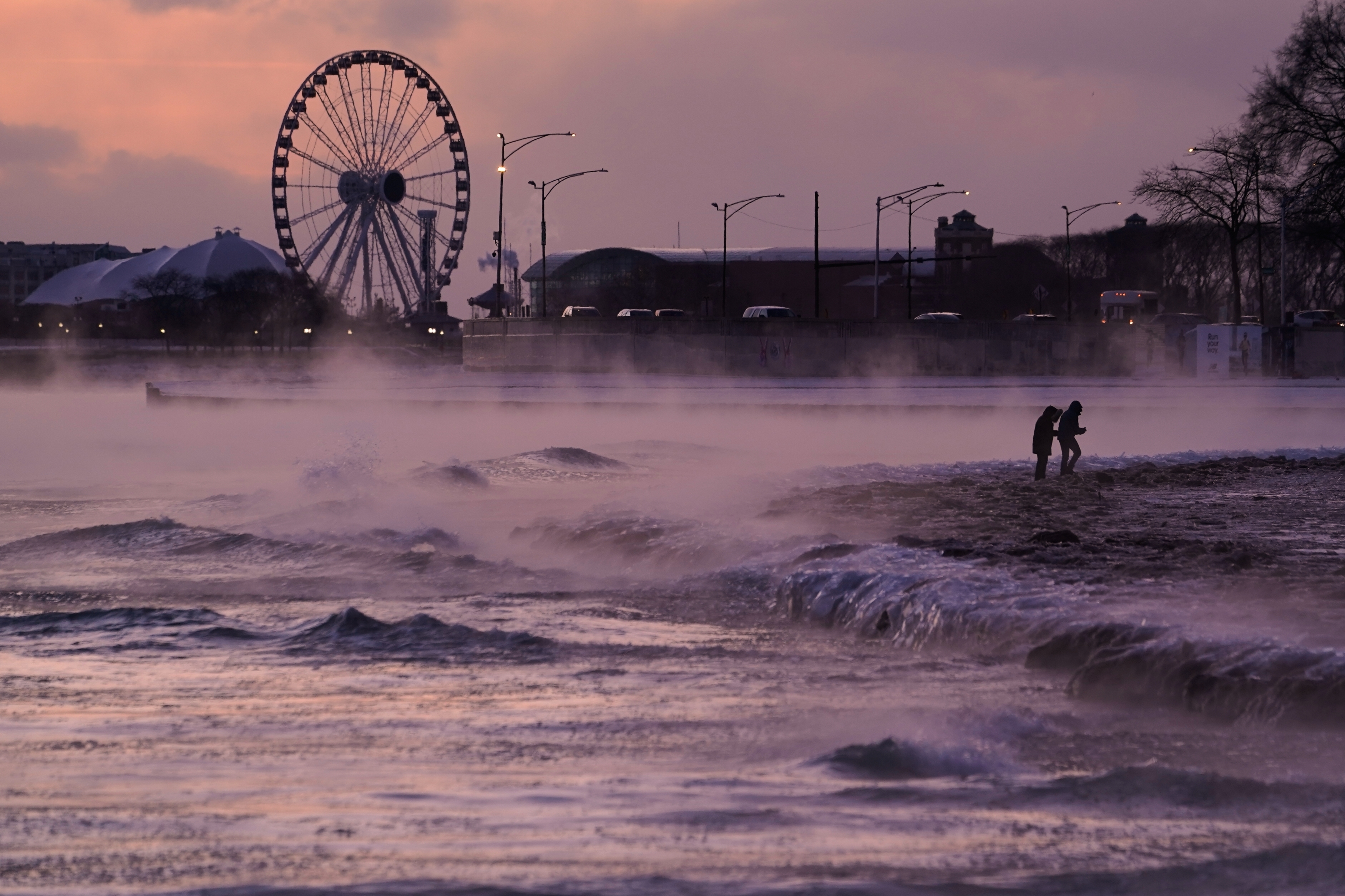 People walk on an ice covered beach along the shore...