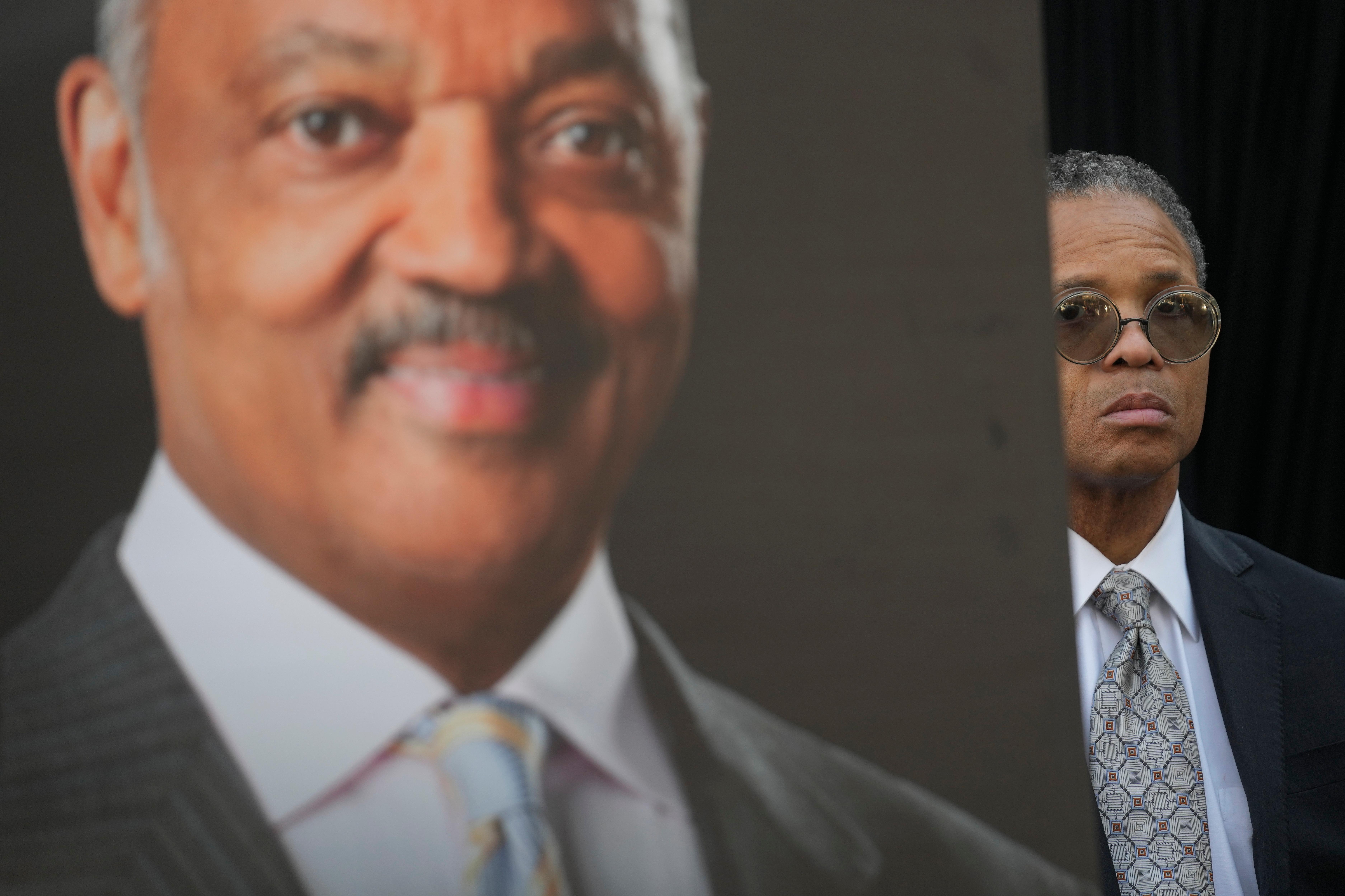 Jesse Jackson, Jr. stands near a picture of his father,...