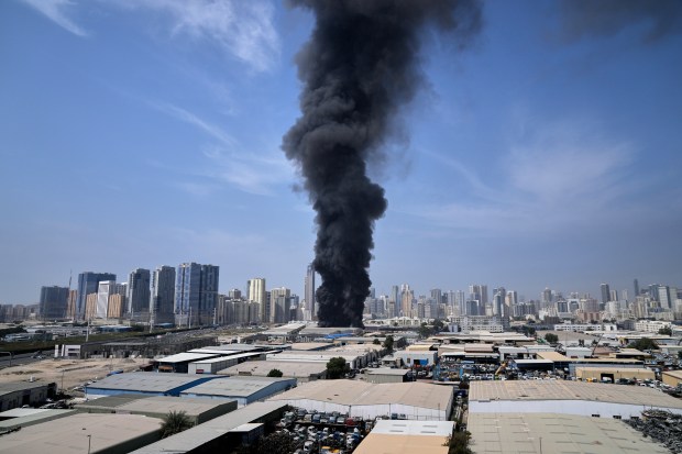 A black plume of smoke rises from a warehouse at the industrial area of Sharjah City in the United Arab Emirates following reports of Iranian strikes in Dubai, United Arab Emirates, Sunday, March 1, 2026. (AP Photo/Altaf Qadri)