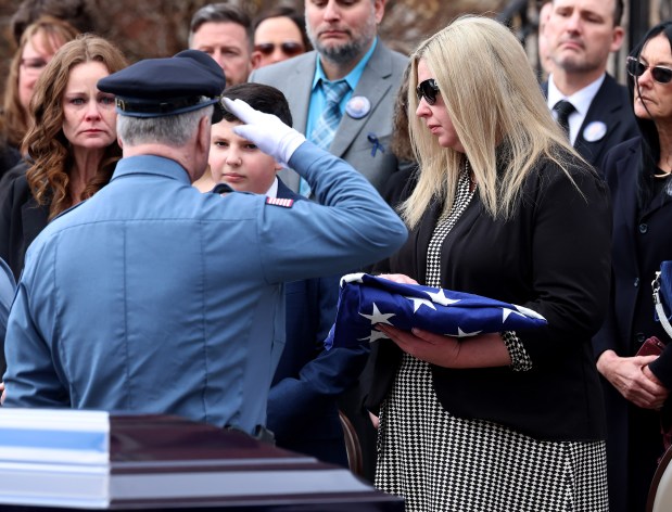 Uxbridge Police Chief Marc Montminy salutes after presenting the American flag to Shannon LaPorta following a funeral service for her husband Stephen LaPorta. At left is Matthew LaPorta, son of Stephen. LaPorta died after getting hit by a tractor-trailer on Jan. 7 while assisting a motorist. (Mark Stockwell/Boston Herald)