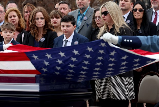 Massachusetts state troopers fold an American flag as as Matthew LaPorta, center, and his mother Shannon LaPorta watch during the funeral service for fallen Uxbridge police officer Stephen LaPorta. (Mark Stockwell/Boston Herald)