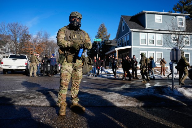 A federal immigration officer holds a can of pepper spray, trying to keep protesters back, near the scene where Renee Good was fatally shot by an ICE officer last week, Tuesday, Jan. 13, 2026, in Minneapolis. (AP Photo/John Locher)