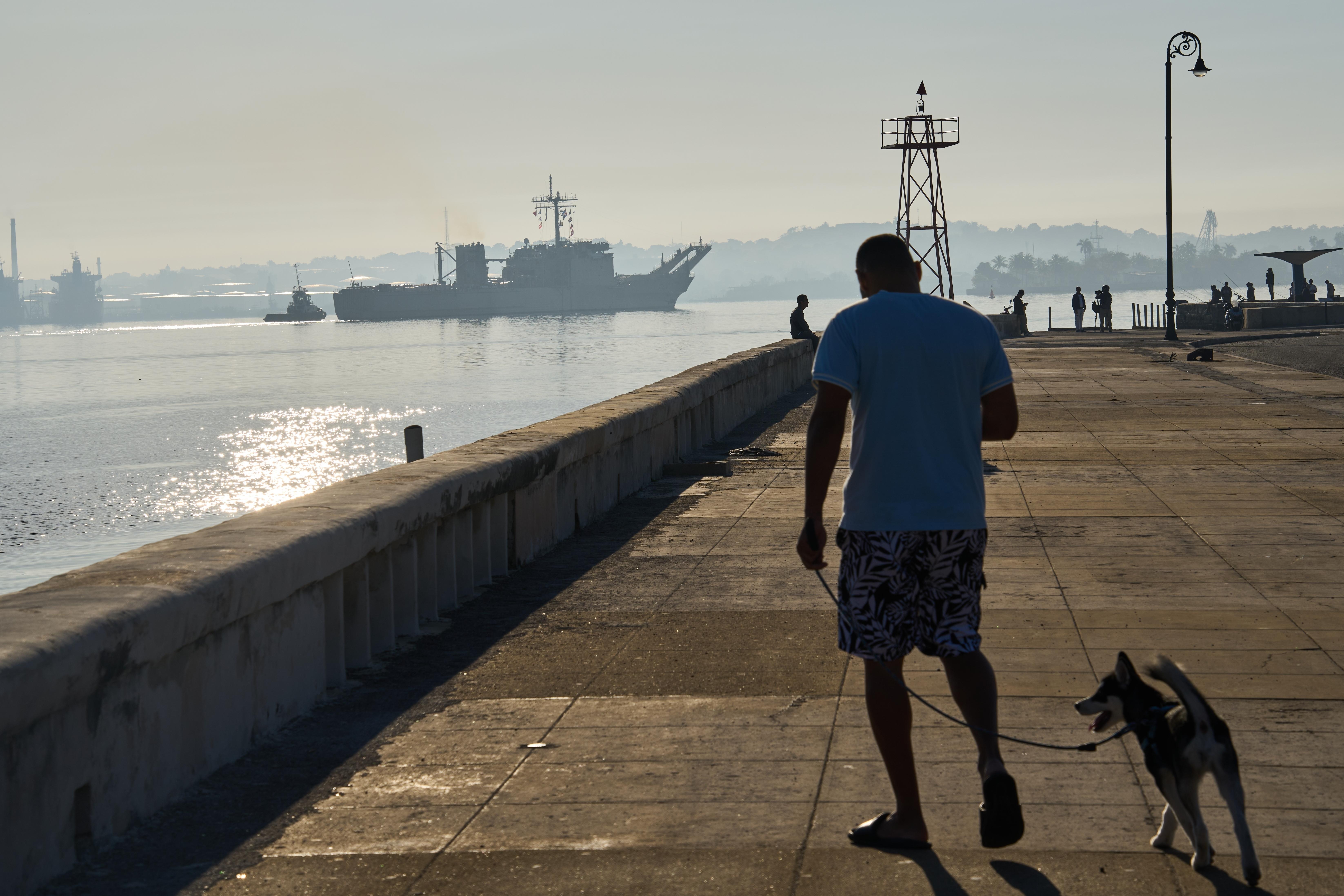 A man walks his dog along Havana Bay where the...
