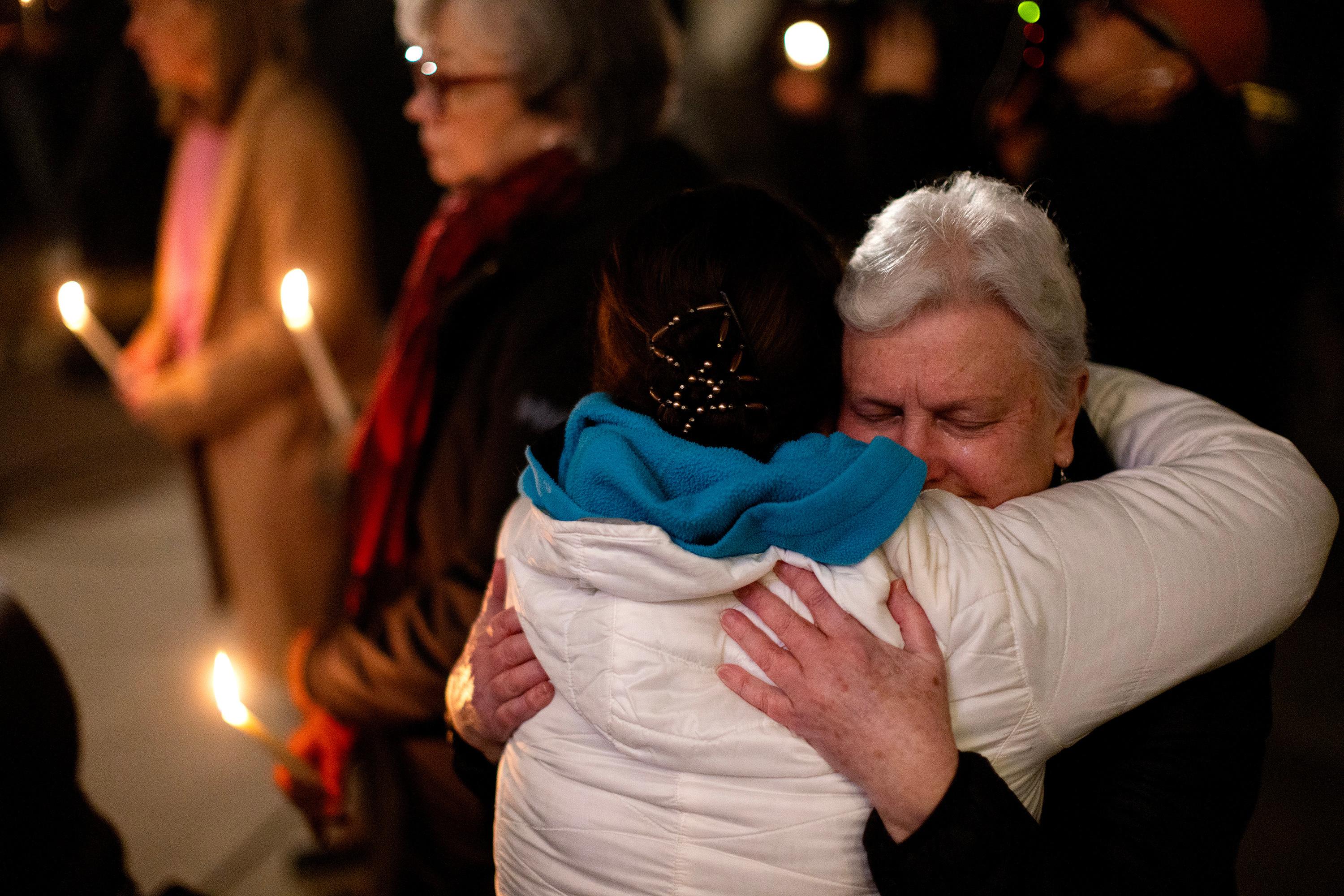 People console one another during a candle light vigil at...