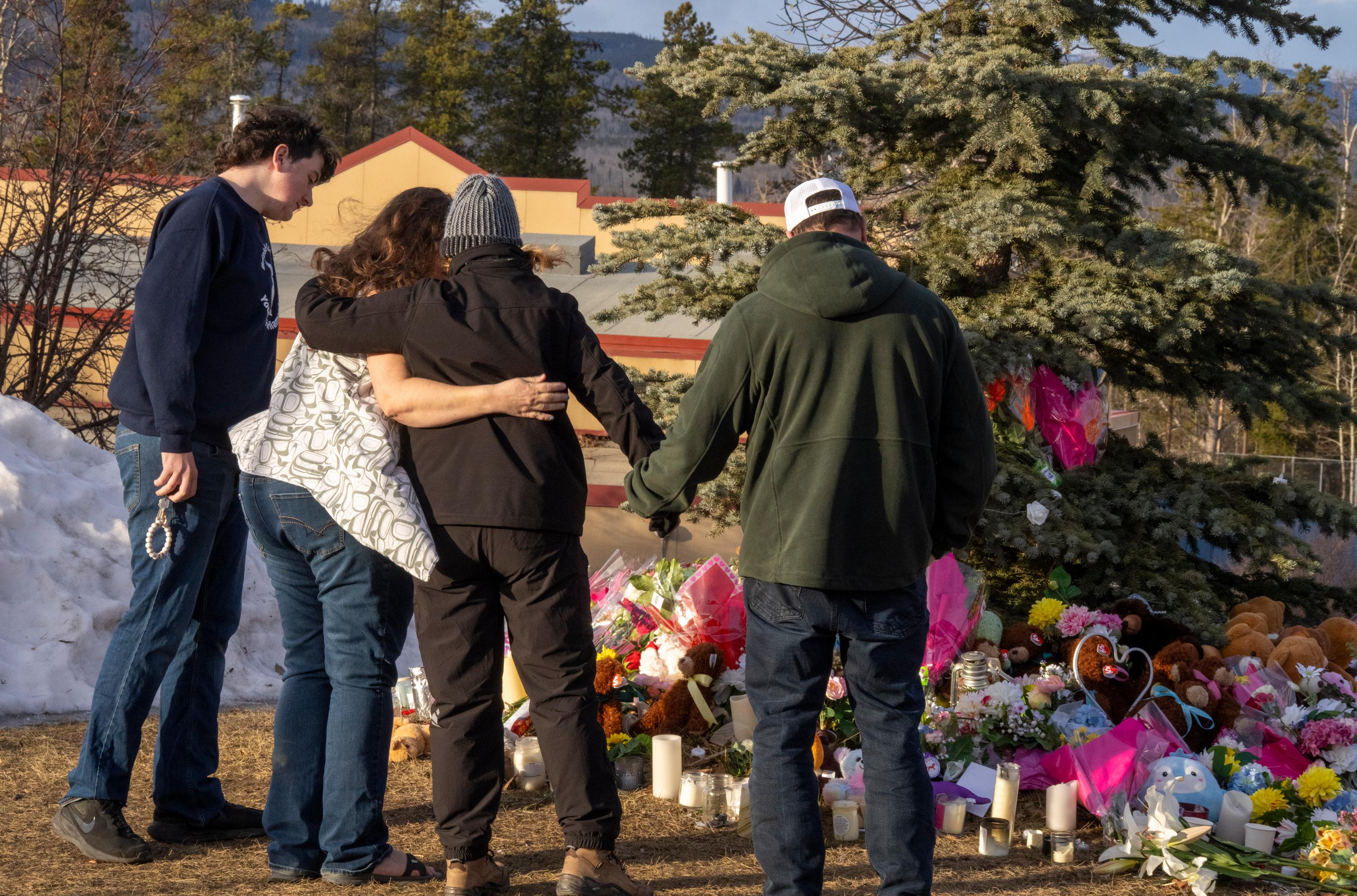 Residents hug as they place flowers at a memorial for...
