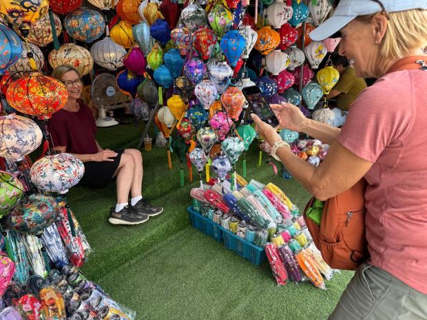AdventureWomen guests take turns posing for photos in a stall full of lanterns in Hoi An, a town that's famous for these colorful souvenirs. (Lori Rackl/Lori Rackl/TNS)