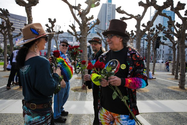 Anthony "Tony" Zopolos, right, of Daly City, distributes roses to fellow Deadheads as they attend a Bob Weir memorial in San Francisco on Saturday. (Yalonda M. James/San Francisco Chronicle via AP)