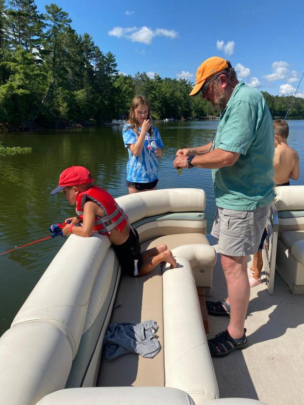 Tom LaDue baits a hook with his grandkids in 2022 before PFAS contamination was discovered in Snowden Lake in Stella, Wis. (Courtesy Tom LaDue via AP)