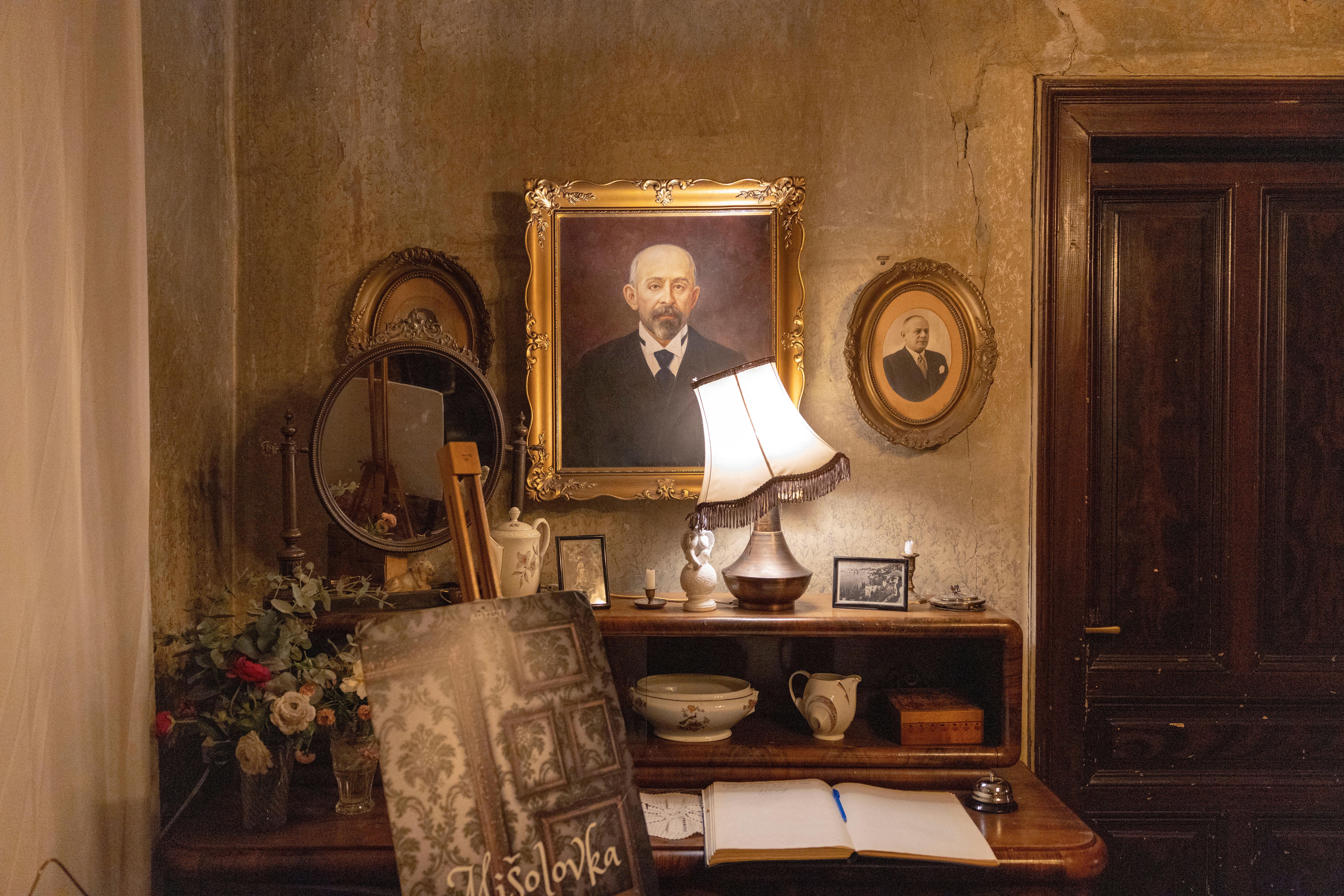 Pieces of furniture and portraits are seen in an old...