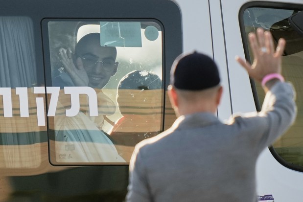Rom Breslavski, an Israeli hostage released from the Gaza Strip waves from a minibus at the Sheba Medical Center in Ramat Gan, Israel, on Monday. (AP Photo/Leo Correa)