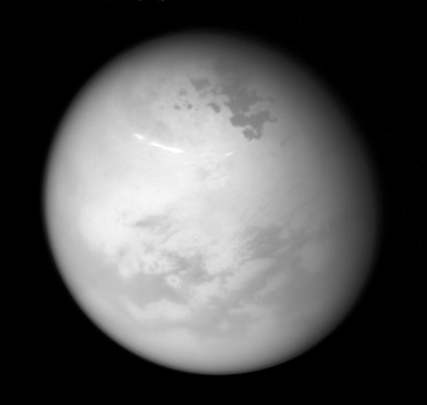 FILE - This image provided by NASA shows bright methane clouds drifting in the summer skies of Saturn's moon Titan, along with dark hydrocarbon lakes and seas clustered around the north pole, as seen from the Cassini spacecraft, June 9, 2017. (NASA/JPL-Caltech/Space Science Institute via AP, File)