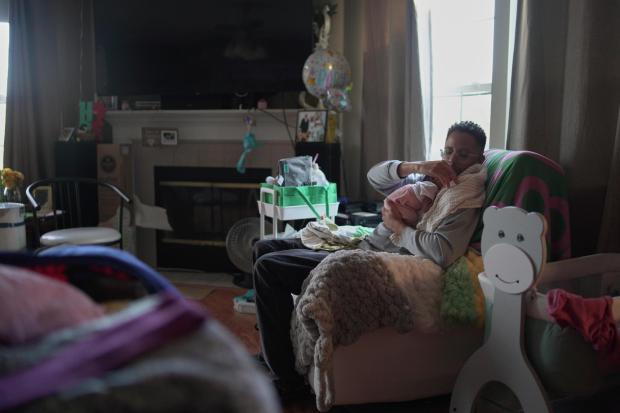 JaKobi Burton cradles his newborn daughter, Phoenix RyZen Reign Burton, on his shoulder.