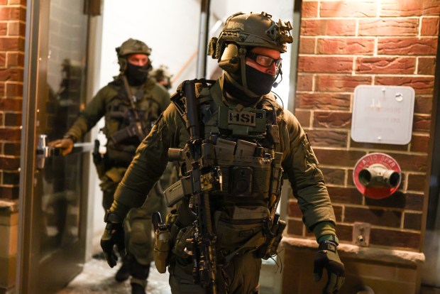 Federal agents with Homeland Security Investigations (HSI) exit a residential building as they seek to detain a protester in Minneapolis, Minnesota, on February 5, 2026. (Photo by Charly Triballeau / AFP via Getty Images) 