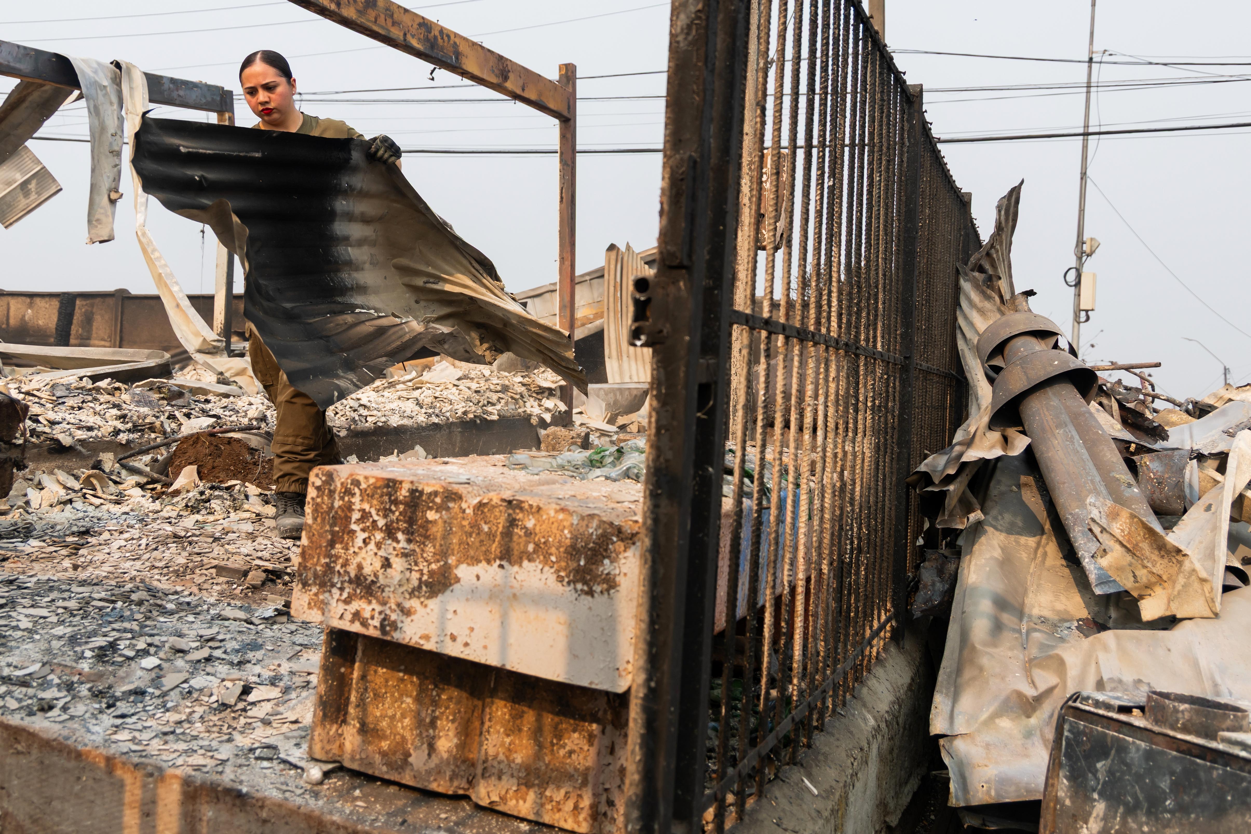A police officer clears burned roofing sheets from a home...