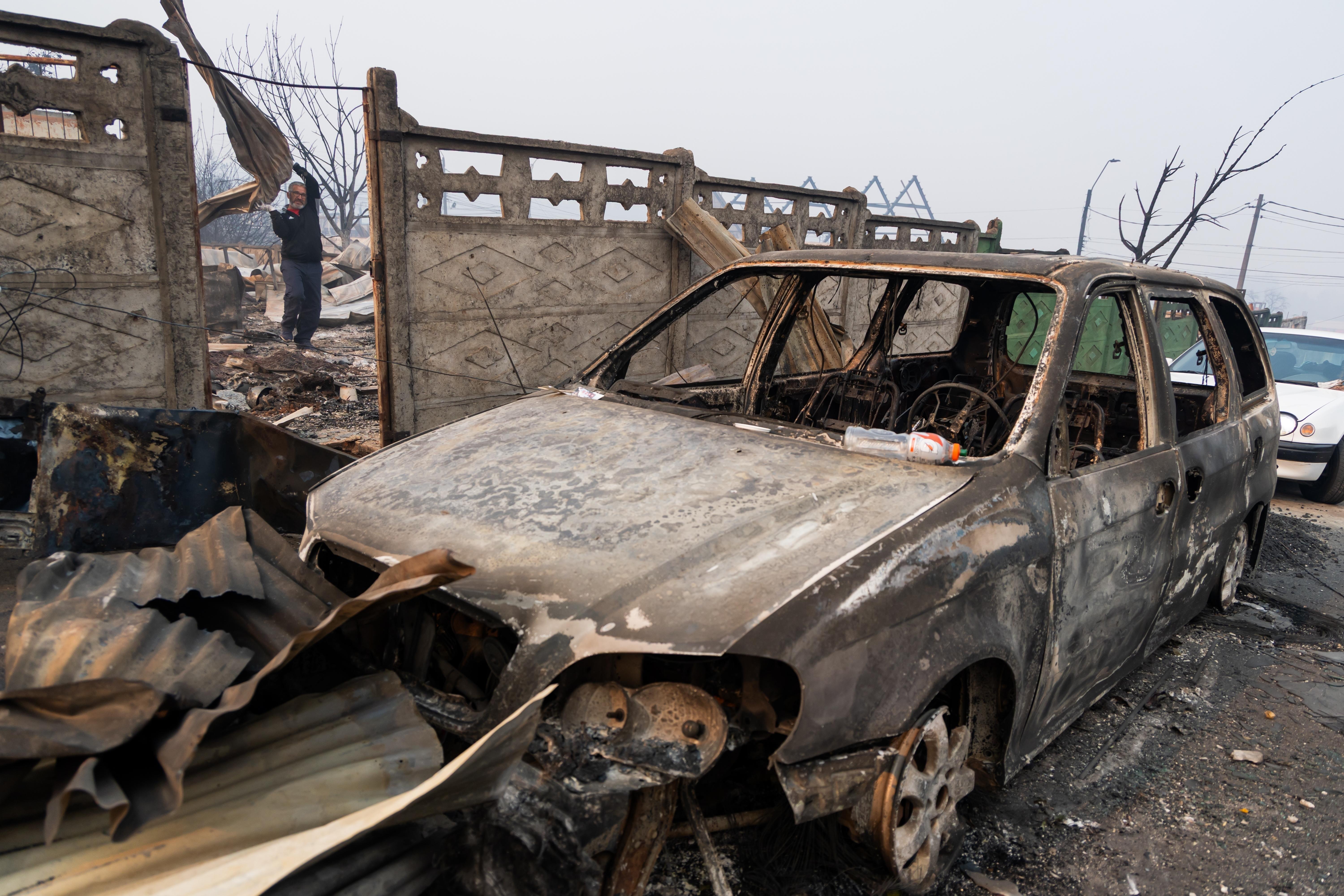 Andres Garrido carries burned roofing sheets at his home after...
