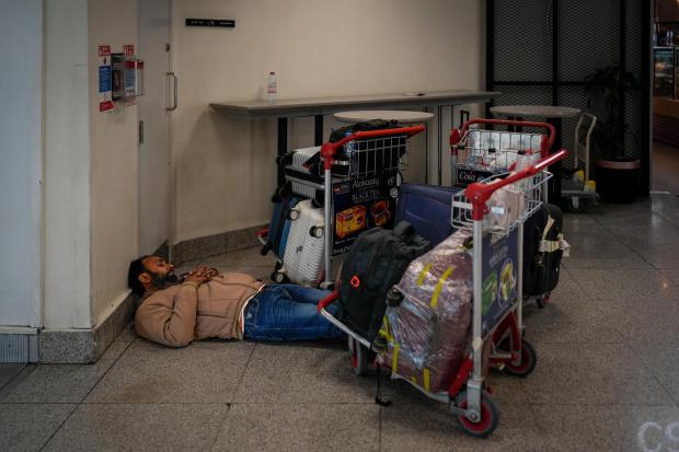 A stranded passenger sleeps on the floor outside a Dubai International Airport terminal.