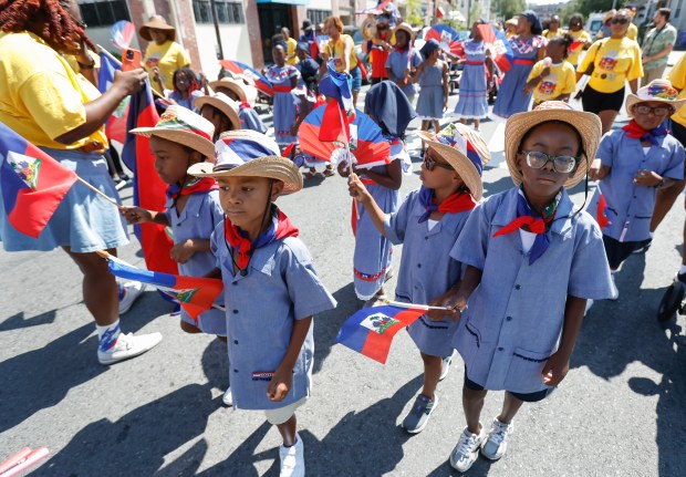 Youngsters from SmoovNetwork wave Haitian flags while marching in the parade. (Paul Connors/ Boston Herald)