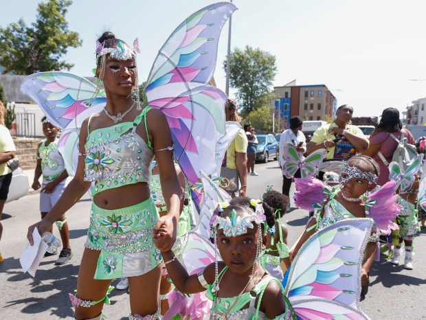 Jynth Benjamin, 12, left, and Ty' Jae Smith, 4, holds hands while marching in Mirage Mas' presentation named "Back in Time" during the carnival. (Paul Connors/Boston Herald)