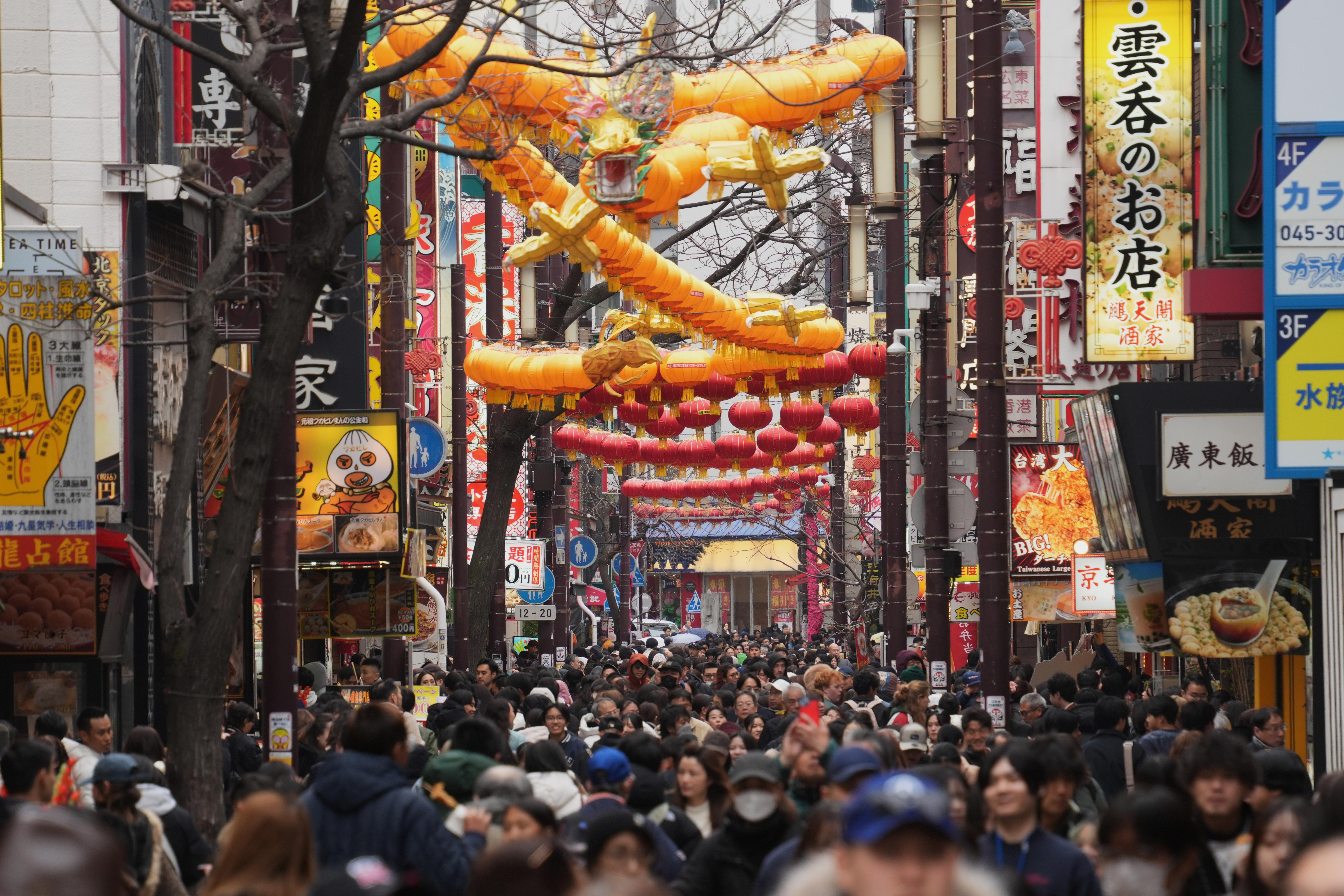 Visitors stroll a street decorated with a big dragon shaped...