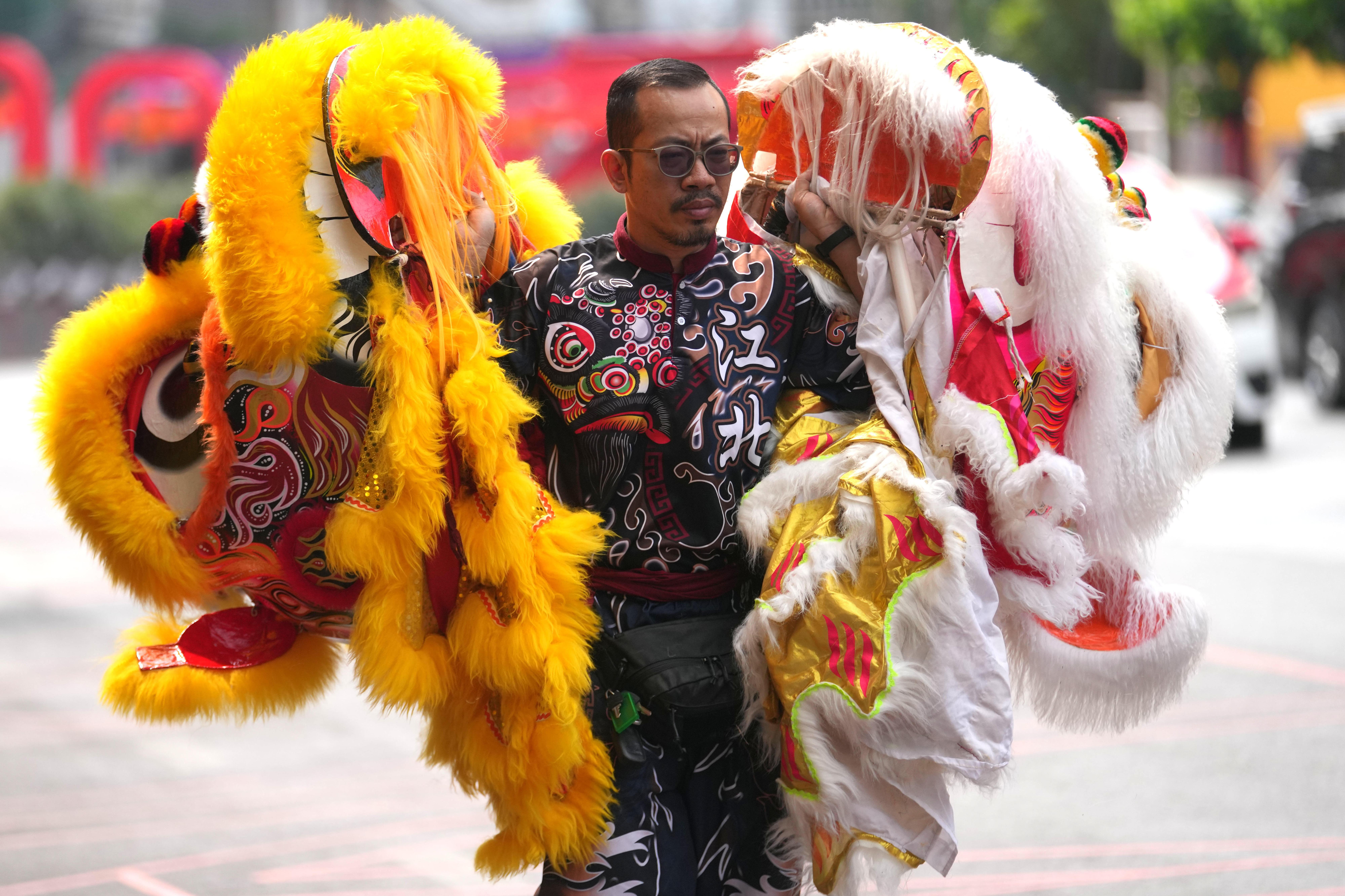 A dancer holds the heads of lion dance costumes during...