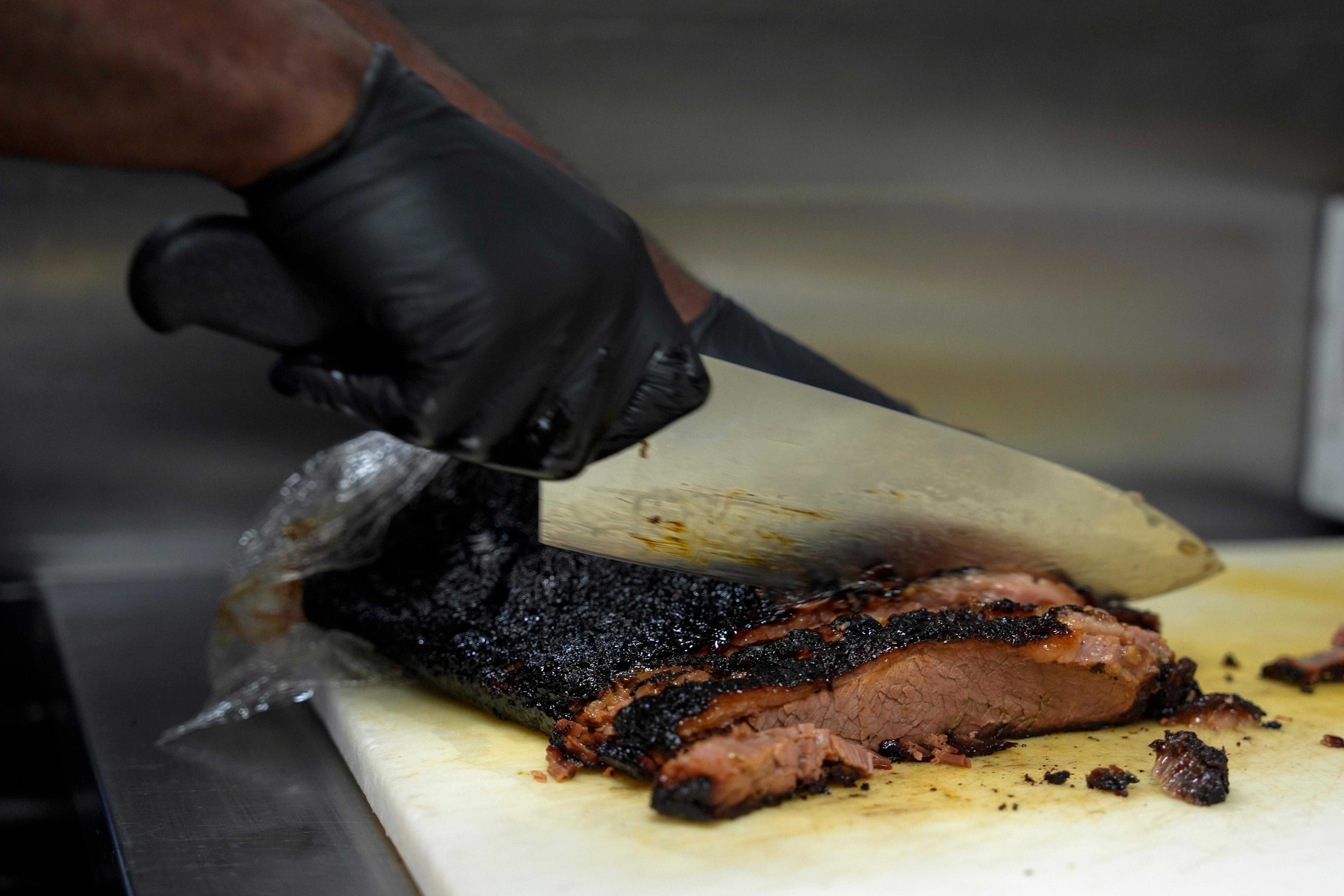 FILE – A line cook slices beef brisket June 12,...