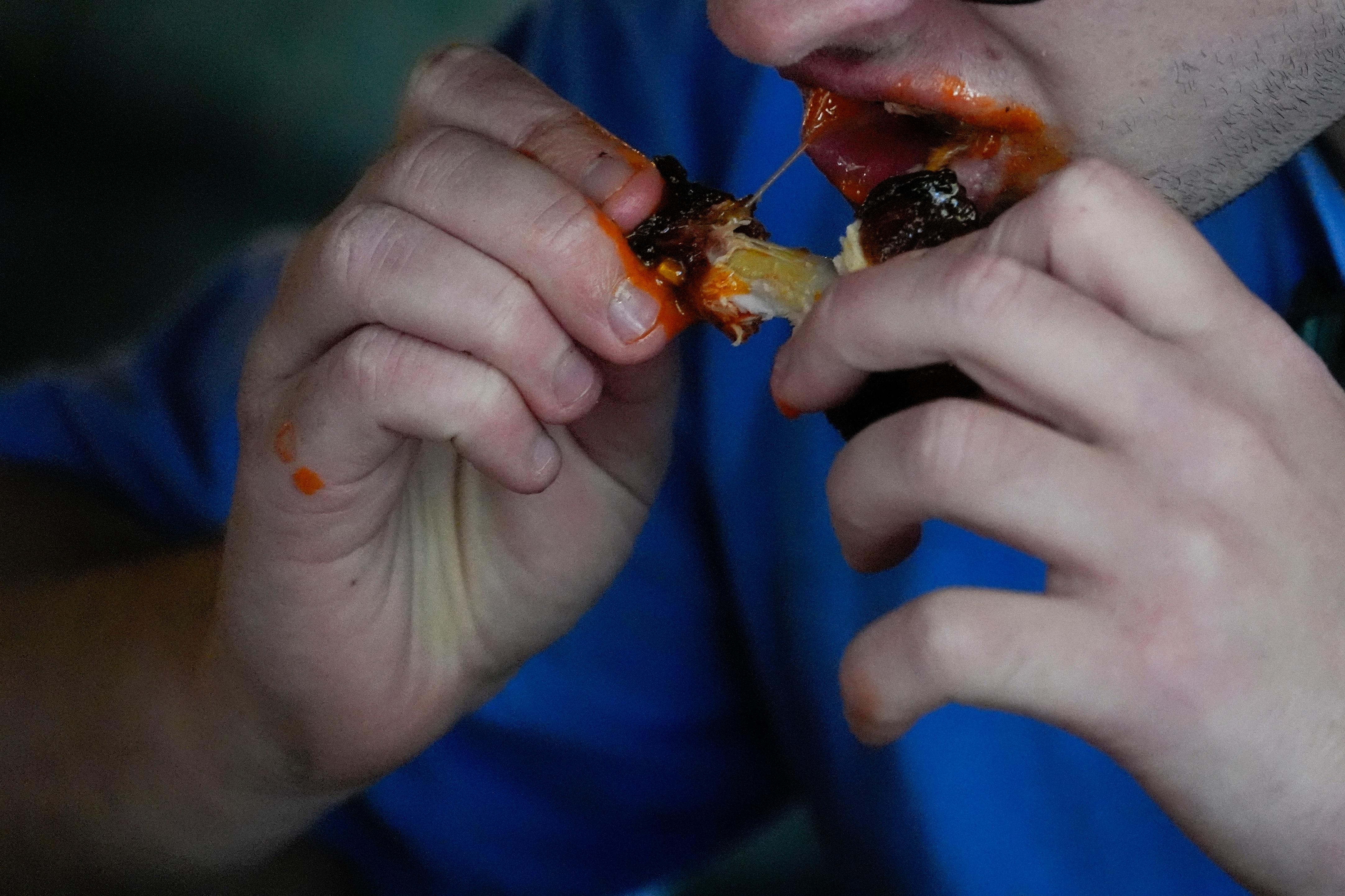 FILE – A man eats a chicken wing June 12,...