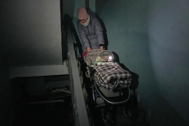 Yuliia Dolotova, 37, pulls her son in his stroller up the stairs in an apartment block during a power outage caused by Russia's repeated air strikes on the country's power grid, in Kyiv, Ukraine, Monday, Feb. 2, 2026. (AP Photo/Sergey Grits)