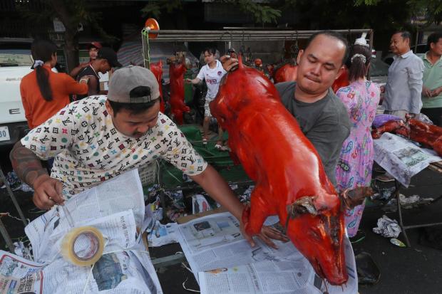A vendor holds a grilled pig for selling for Lunar New Year celebrations