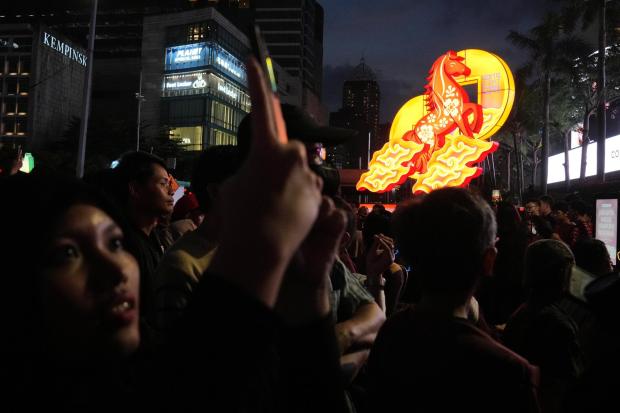 A woman uses her mobile phone to take photos of a performance during the celebration of the Chinese Lunar New Year of the Horse