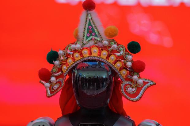 A humanoid robot wearing a traditional headdress is displayed during a media preview of a robotic temple fair