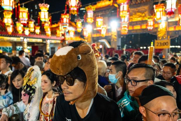 A worshiper wears a horse head decoration at Wong Tai Sin Temple