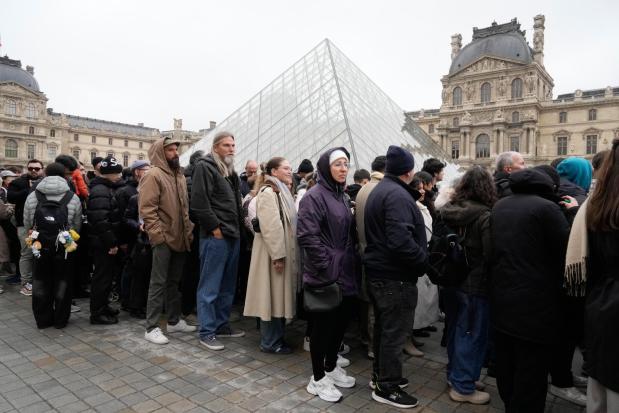 People queue outside the Louvre museum in Paris, France.