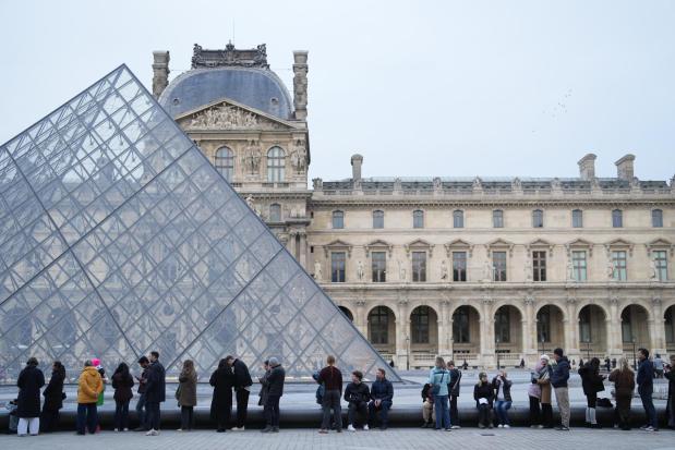People queue outside the Louvre museum in Paris, France.