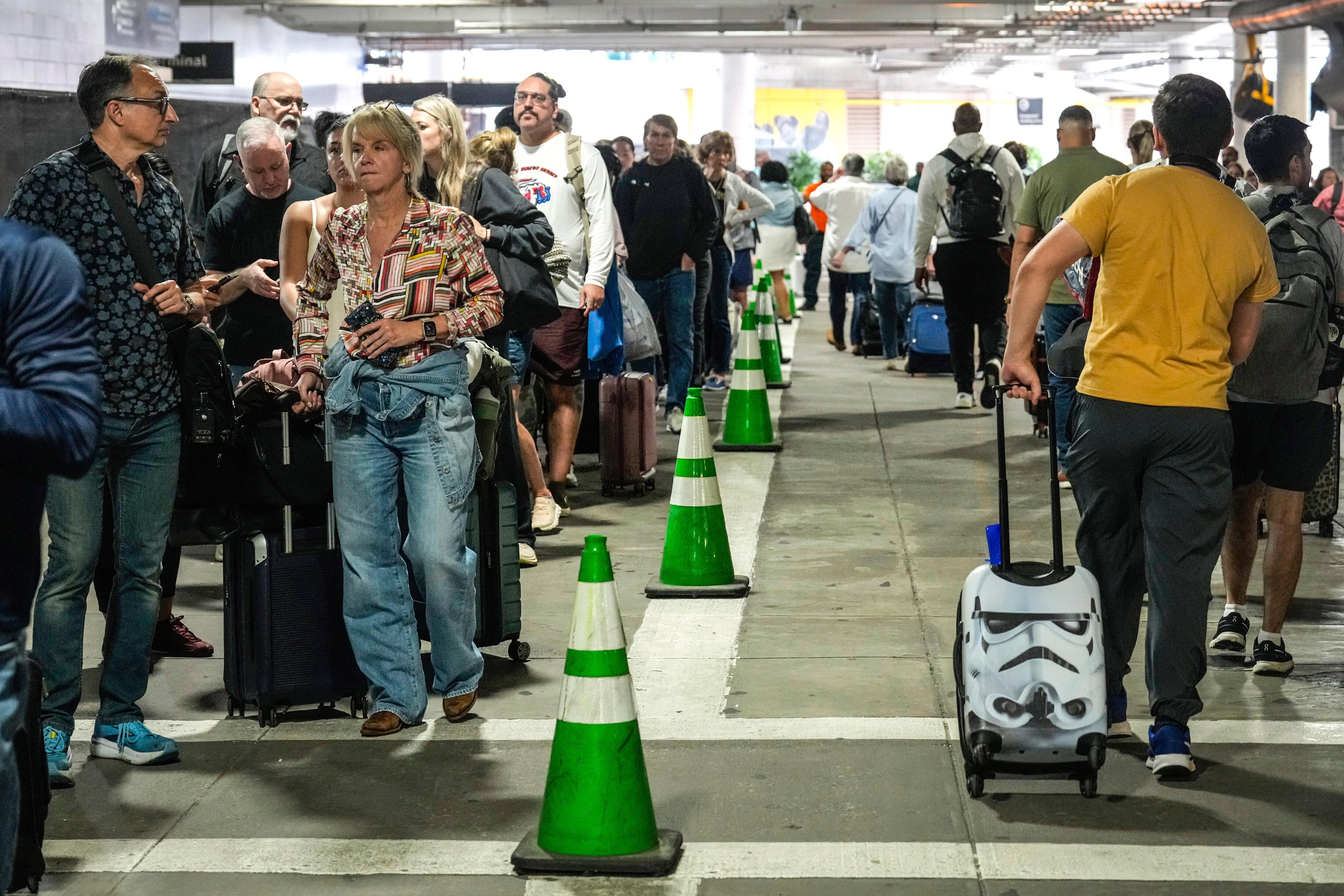 Airline passengers wait outside the terminal in the parking garage in long lines for TSA.