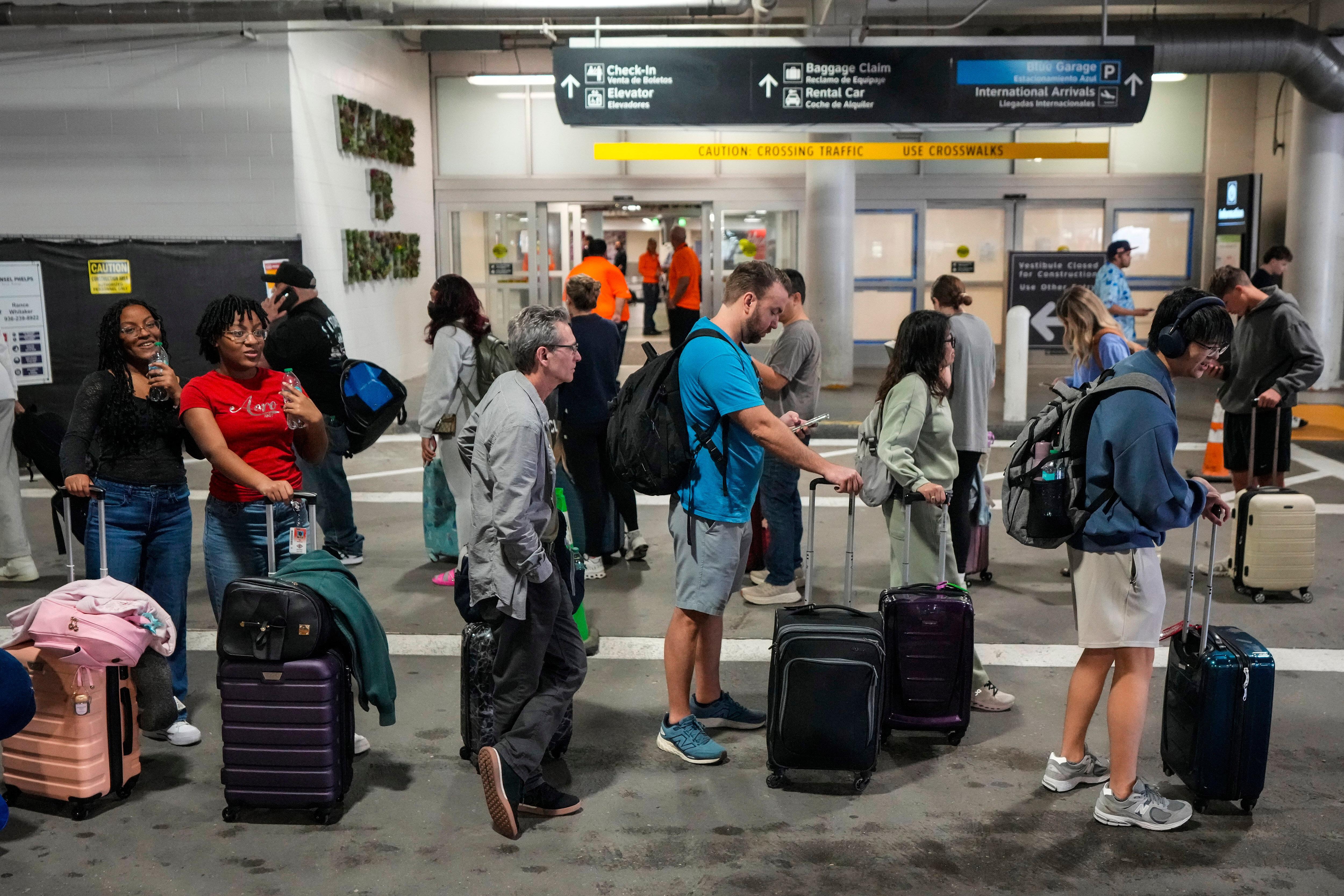 Airline passengers wait in long lines outside the terminal to get through TSA screening.