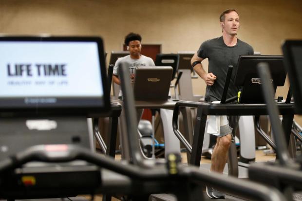 People run on treadmills at a gym.