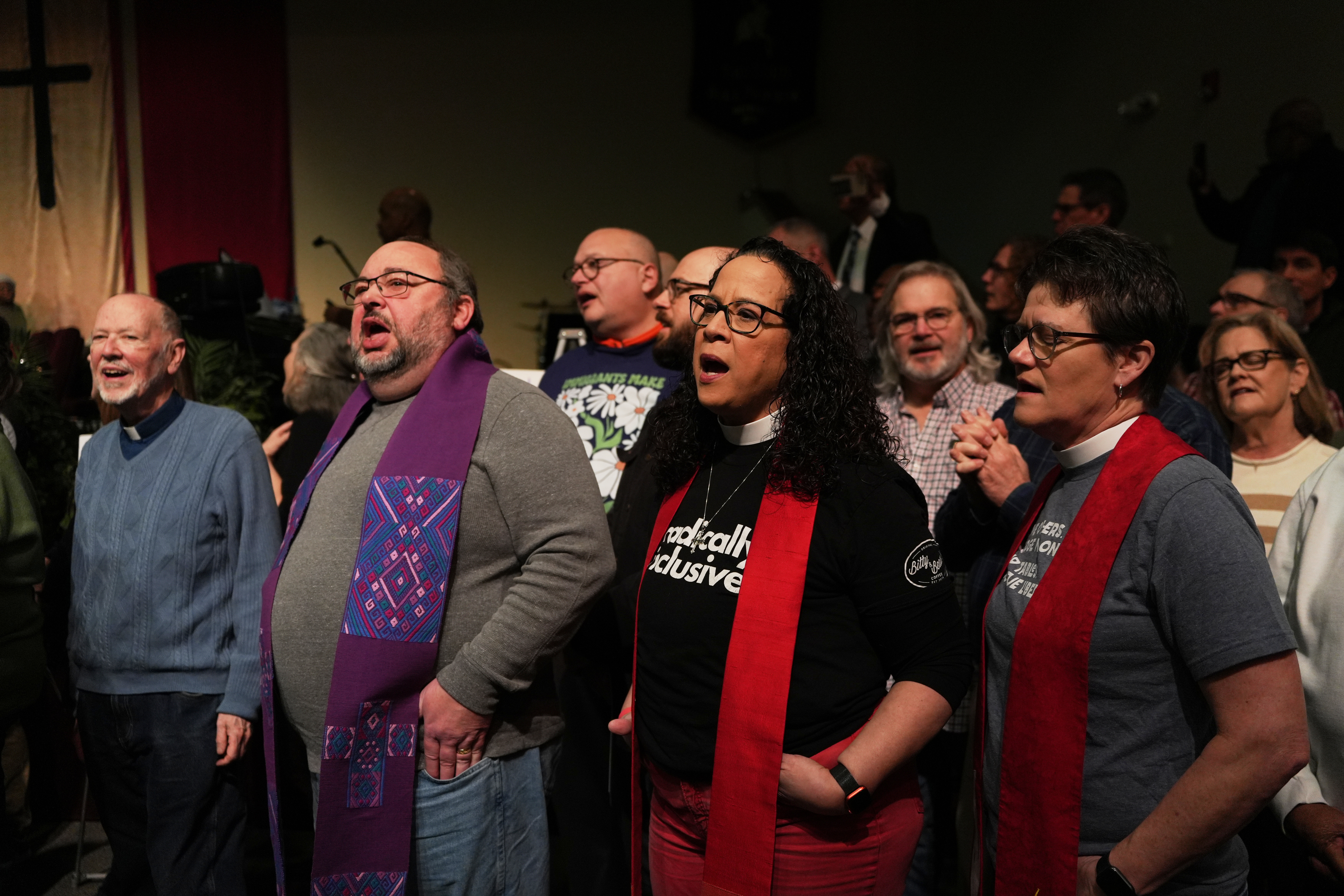 Faith leaders sing together as a sign of support for...