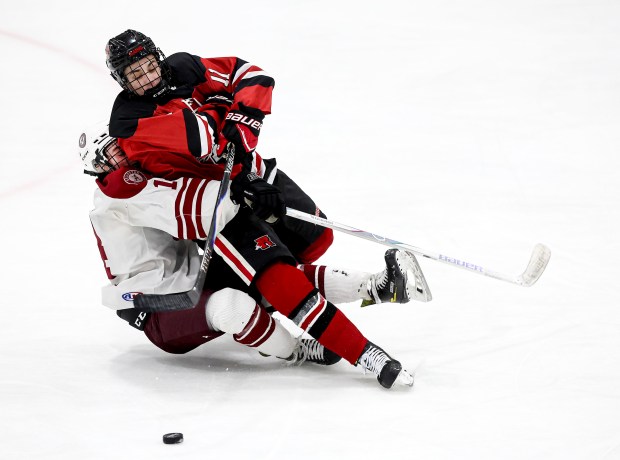Arlington's Seamus Sullivan, left, and Reading Memorial's Brendan MacCurtain, right, collide chasing the puck during the first period of a boys ice hockey game, Saturday, in Arlington. (Mark Stockwell/Boston Herald)